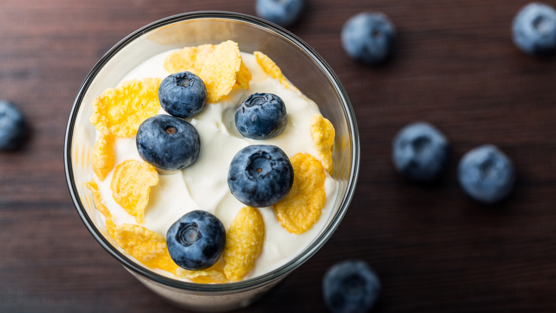 A healthy snack with yoghurt, blueberries and flakes in a cup