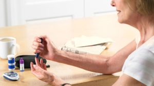 A diabetic patient taking a reading of their blood glucose levels which can be linked to gum disease.