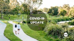 Covid-19 update logo over Grant and Jasmine walking on the Kedron Brook
