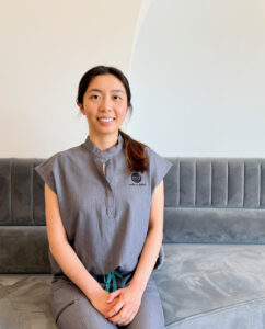 Dr. Annie Chen of Method Dental, sitting and smiling in the reception area on a comfortable grey lounge